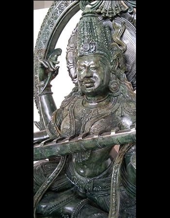 Sophisticated green stone carving of a sage in meditation with detailed robes and peaceful expression