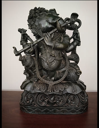 Traditional green stone sculpture of a deity with multiple attributes and divine symbolism